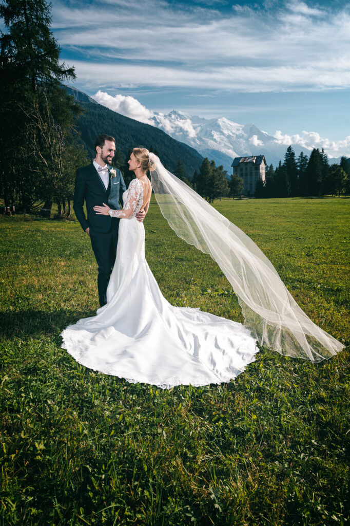 Mariés posant dans un champ avec vue sur le Mont Blanc – Photographe mariage Chamonix vallée de l’Arve