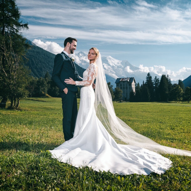 Mariés posant dans un champ avec vue sur le Mont Blanc – Photographe mariage Chamonix Haute-Savoie