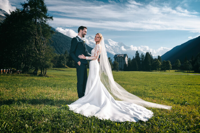 Mariés posant dans un champ avec vue sur le Mont Blanc – Photographe mariage Chamonix Haute-Savoie