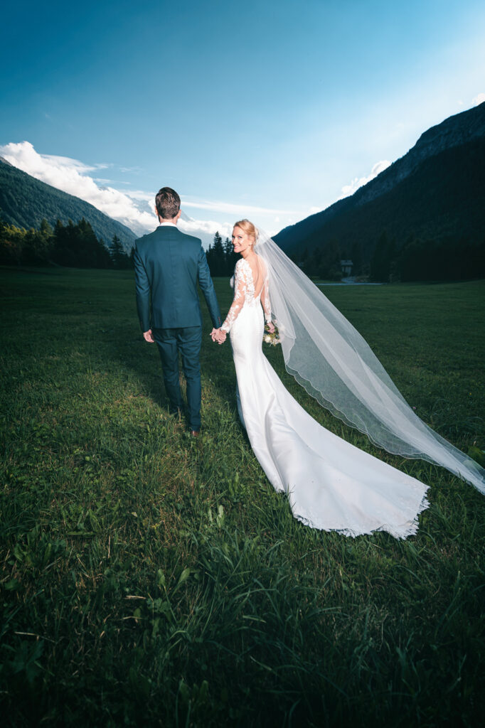 Mariés marchant dans un champ avec vue sur les montagnes du Mont Blanc – Photographe mariage Chamonix