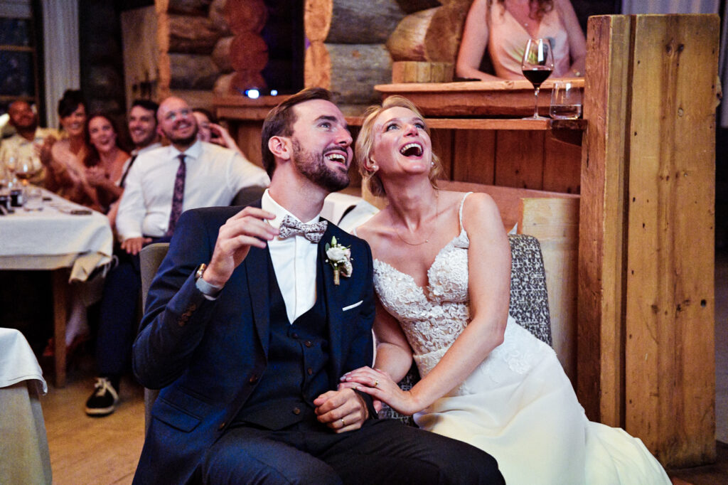 Les mariés Éponine et Martin rient en regardant une projection pendant leur repas de mariage à la Cabane des Praz Chamonix