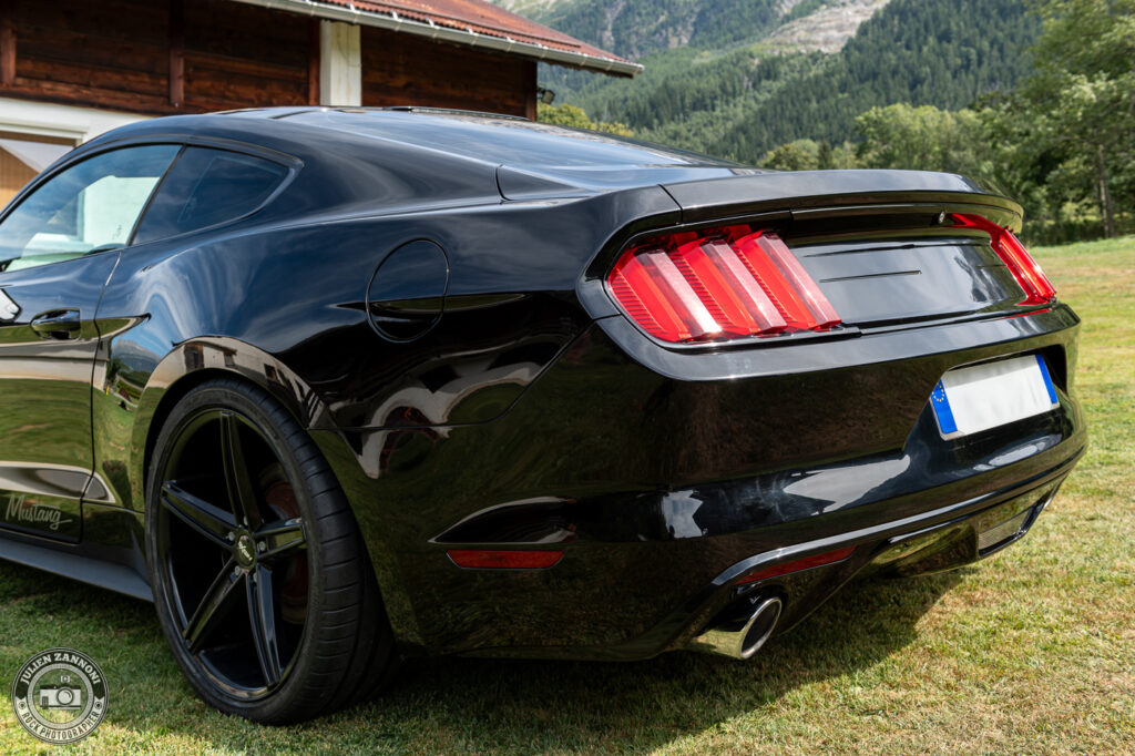 Vue arrière de la Ford Mustang noire 2015 disponible à la location à Chamonix pour mariage, shooting et tournage.