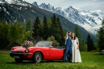 Couple de mariés en prairie alpine avec spider rouge et vue sur le Mont-Blanc, Argentière Chamonix