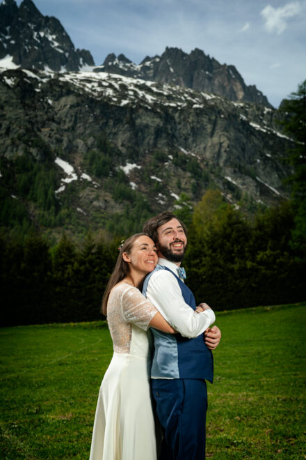 Couple de mariés en prairie alpine avec vue sur le Mont-Blanc, Argentière Chamonix